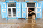 Мужчина вычерпывает воду из жилого дома, пострадавшего от наводнения в городе Крымске, июль 2012 года