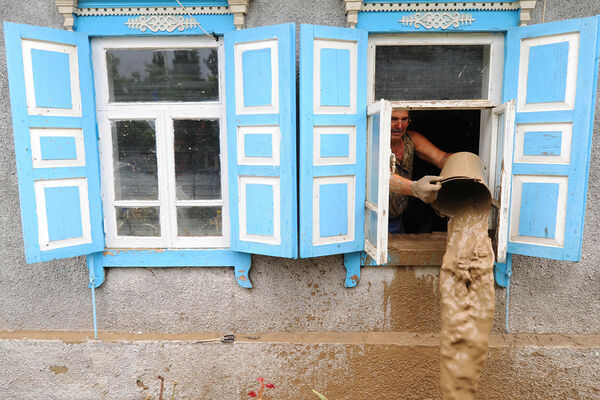 Мужчина вычерпывает воду из&nbsp;жилого дома, пострадавшего от наводнения в&nbsp;городе Крымске, июль 2012&nbsp;года