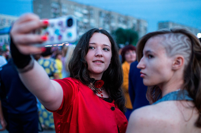 Выпускники омских школ фотографируются на мобильный телефон во время гуляний на Иртышской набережной города