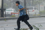 Идущего по пешеходному переходу мужчину сносит сильным ветром, вызванным тайфуном «Неогури», на южном японском острове Окинава