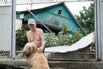 Мужчина с собакой у забора жилого дома, разрушенного наводнением в городе Крымске, июль 2012 года