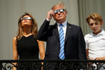 Президент США Дональд Трамп со своей женой Меланьей Трамп и сыном Бэрроном наблюдают за солнечным затмением с крыльца Белого дома, 21 августа 2017 года