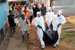 Бригада врачей выносит тело 29-летнего местного жителя, погибшего от вируса Эбола в Монровии
