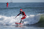 Человек в костюме Санта-Клауса занимается серфингом на пляже Какао-Бич, Флорида (США)