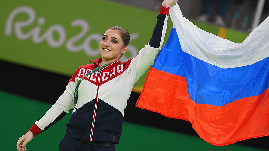 Алия Мустафина, завоевавшая золотую медаль в упражнениях на брусьях на соревнованиях по спортивной гимнастике среди женщин на XXXI летних Олимпийских играх, на церемонии награждения