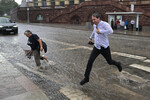 Мужчина перепрыгивает поток воды на подтопленной дороге в результате ливня возле метро «Баррикадная» в Москве, 18 июля 2023 года