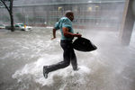 Житель Нового Орлеана бежит в убежище после того, как ураган «Катрина» сорвал крышу его дома 29 августа 2005 года
