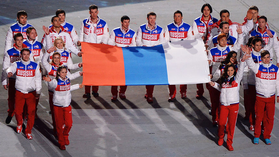 Российские медалисты выносят российский флаг во время церемонии закрытия XXII зимних Олимпийских игр в Сочи