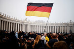 Мужчина с флагом Германии на площади Святого Петра в день похорон папы Бенедикта XVI в Ватикане, 5 января 2022 года