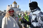 Сотрудник Росгвардии поздравляет девушку с наступающим 8 марта на Патриаршем мосту в Москве, 7 марта 2024 года