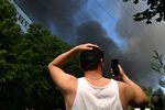 Мужчина снимает пожар в промышленной зоне на Каширском шоссе в Москве, 29 июня 2022 года 