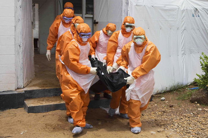 Похоронная команда в&nbsp;защитных костюмах выносит тело умершего из&nbsp;изолятора в&nbsp;окружном госпитале Порт-Локо, Сьерра-Леоне