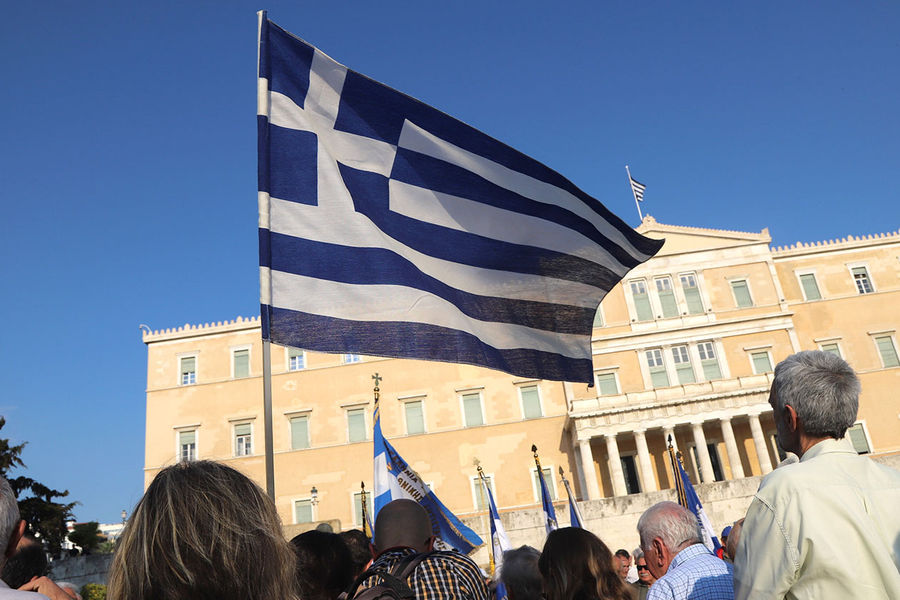 Демонстранты с флагом Греции у здания парламента требуют перейти к переговорам по вопросу о репарациях за ущерб, нанесенный стране нацистской Германией, а также в годы Первой мировой войны. Афины, 27 апреля 2018 года