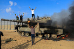 Палестинцы празднуют на израильском танке после того, как его подбили палестинские боевики, проникшие в южные районы Израиля, 7 октября 2023 года. 