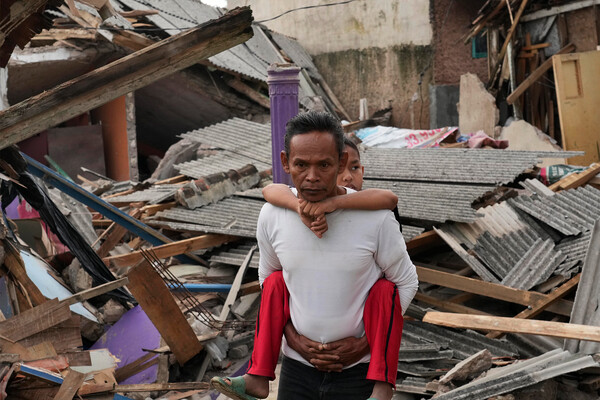 Мужчина с&nbsp;ребенком на&nbsp;фоне разрушенных домов в&nbsp;Чианджуре, Инднезия, 22&nbsp;ноября 2022&nbsp;года