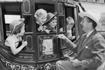 Уолт Дисней с игрушечным револьвером в руках улыбается, притворяясь, что грабит детей в дилижансе, «Диснейленд», Анахайм, Калифорния, 1955 год