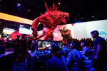 Посетители выставки играют в игру «Evolve» на стенде компании Ubisoft