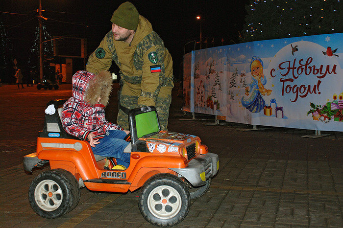 Ополченец ДНР катает ребенка на&nbsp;игрушечном автомобиле в&nbsp;канун Нового года в&nbsp;центре Донецка