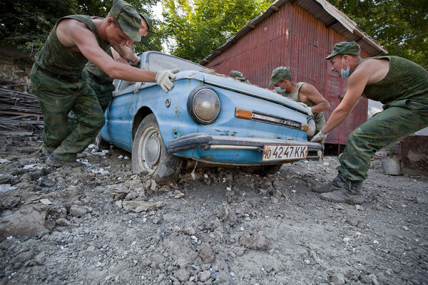 Военнослужащие сдвигают поврежденный наводнением автомобиль во время работ по&nbsp;очистке улиц Крымска, июль 2012&nbsp;года