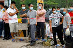 Люди за ограждением перед въездом в деревню Лу рядом с местом крушения самолета Boeing 737, Гуанси-Чжуанский автономный район, Китай, 22 марта 2022 года

