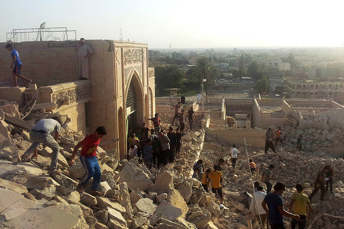 Люди ходят по развалинам разрушенной мечети в Мосуле