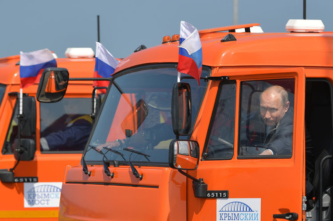 Президент России Владимир Путин садится за руль головной автомашины «Камаз» во время проезда колонны строительной техники по автодорожной части Крымского моста на торжественной церемонии открытия транспортного перехода, 15 мая 2018 года
