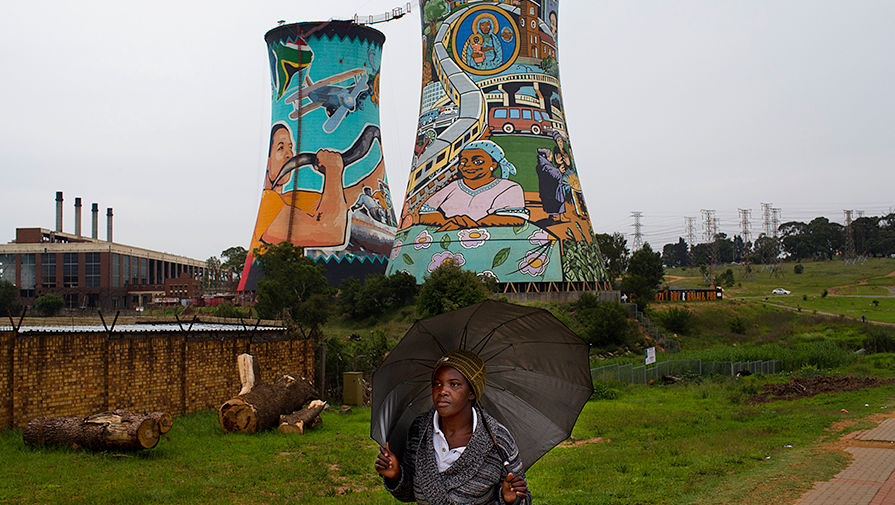 Женщина рядом с градирнями закрытой электростанции в Йоханнесбурге, ЮАР