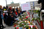 Жители Берлина несут цветы в память о жертвах теракта к посольству Франции