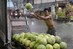 Продавец арбузов на рынке в Кесон-Сити во время дождя, Филиппины, 13 июля 2023 года