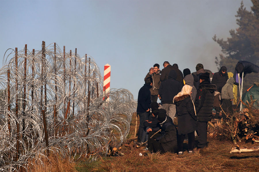 Мигранты на границе Польши и Белоруссии у забора из колючей проволоки, 9 ноября 2021 года