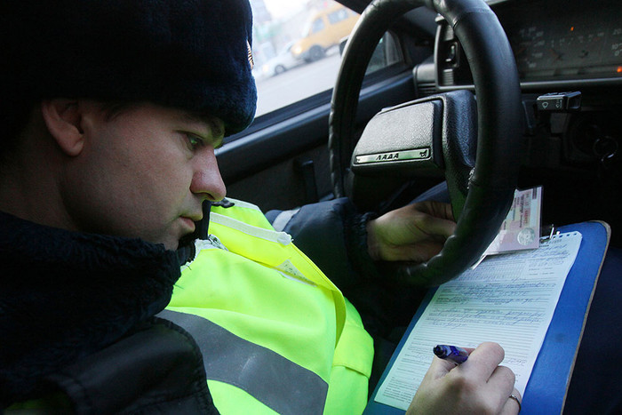 Сотрудник дорожно-постовой службы составляет протокол нарушения правил дорожного движения
