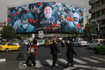 Люди проходят мимо рекламного щита с портретом покойного президента Ирана Эбрахима Раиси на улице в Тегеране, Иран, 21 мая 2024 года