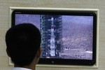 Работник северокорейского объекта, с которого будет запущен спутник, наблюдает за заливкой топлива в ракету-носитель.