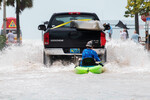 Автомобиль везет человека на байдарке по дороге после наводнения в результате урагана «Иен» в Ки-Уэсте, Флорида, 28 сентября 2022 года