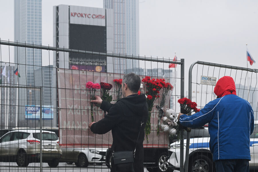Люди несут цветы к зданию концертного зала «Крокус Сити Холл», где произошел теракт, 23 марта 2024 года