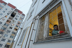 Женщина убирает разбитое стекло рядом с поврежденным многоэтажным жилым домом в Воронеже после падения беспилотника ВСУ, 16 января 2024 года