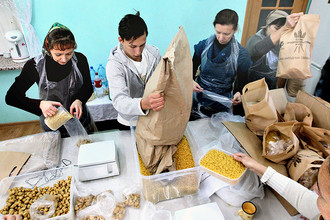 Волонтеры фасуют продукты в пакеты на складе гуманитарной помощи в рамках всероссийского благотворительного проекта для малоимущих