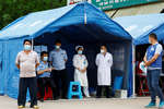 Медицинские работники и полицейские перед въездом в деревню Лу рядом с местом крушения самолета Boeing 737, Гуанси-Чжуанский автономный район, Китай, 22 марта 2022 года
