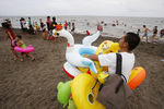 Торговец продает надувные игрушки на пляже во время празднования Пасхи в Танза, Филиппины