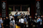 Полицейские охраняют вход в храм Дзодзёдзи, пока люди выстраиваются в очередь для подношения цветов, Токио, 12 июля 2022 года