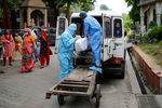 Медики грузят в автомобиль тело умершего от коронавируса мужчины в Нью-Дели, сентябрь 2020 года