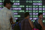 Пассажиры возле табло вылетов в международном терминале в аэропорту Нгурах-Рай на индонезийском курортном острове Бали