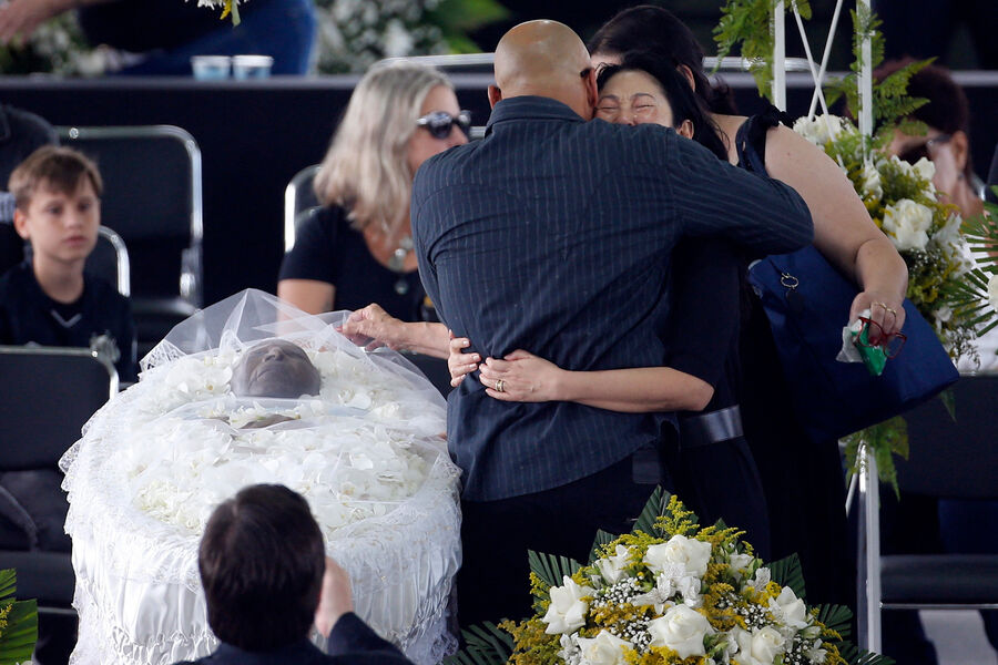 Вдова Пеле Марсия Аоки обнимает сына Пеле Эдиньо у&nbsp;гроба во время церемонии прощания с&nbsp;легендарным футболистом на&nbsp;стадионе «Вила Белмиро» в&nbsp;Сантосе, 2&nbsp;января 2023&nbsp;года
