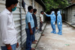Медицинские работники проверяют температуру рабочих у строительной площадки в городе Ахмадабад, сентябрь 2020 года
