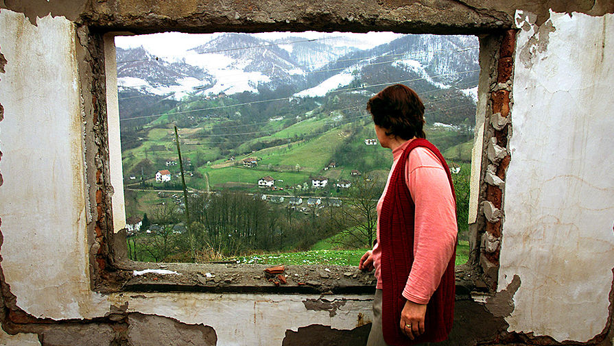 Женщина, которая потеряла большинство родственников в боснийской войне, смотрит в окно своего разрушенного дома в деревне близ Сребреницы, 2002 год