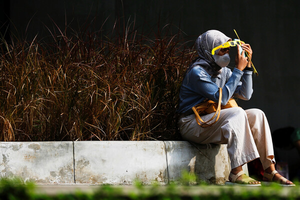 Женщина в&nbsp;специальных защитных очках наблюдает за&nbsp;редким гибридным солнечным затмением в&nbsp;Джакарте, Индонезия, 20&nbsp;апреля 2023&nbsp;года