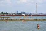 Местные жители купаются на городском пляже. На заднем плане завод «Азовсталь». Мариуполь, июнь 2022 года. 