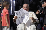 Ребенок дарит свой рисунок папе Франциску после еженедельной общей аудиенции на площади Святого Петра в Ватикане, 6 сентября 2023 года
