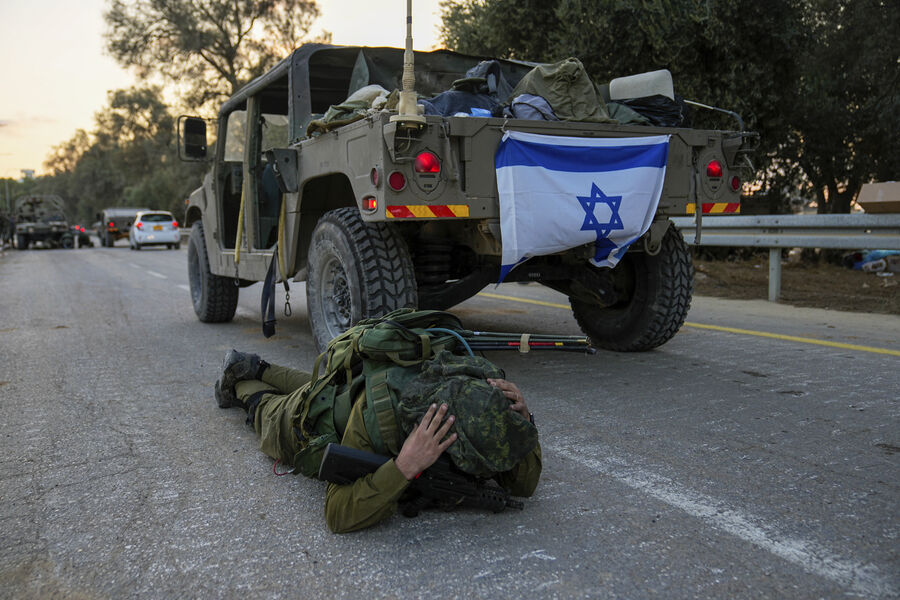 Израильский солдат слышит сирену воздушной тревоги и ложится на землю в кибуце Беэри, Израиль,11 октября 2023 года