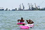 Местные жители купаются на пляже в Мариуполе, июнь 2022 года